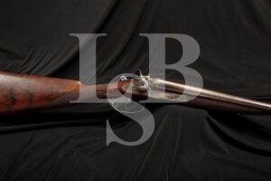 LSB#: 140519PR02 Make: Mortimer & Son Model: Damascus Side By Side Serial Number: 7025 Year of Manufacture: 1875-1887 (Years of the 12 B Not For Ball Proof) Gauge: 12 Gauge, 2 ½” Shells Action Type: Top-Break Dual Trigger Side By Side (SxS) with External Hammers and Extractor. Markings: The right and left lock plates are marked “MORTIMER & SON”. The bottom tang is marked “7025”. The water table is marked with two crowned “V”s. The top of the barrel rib is marked “MORTIMER & SON EDINBURGH”. The underside of the left barrel is marked “12B / NOT FOR BALL / 14M” along with a crowned “GP”, and “V”. The underside of the right barrel is marked with the crowned “GP, V” and “13”. There is light scroll engraving on the receiver and hammers. Barrel Length: 29 ¾” Choke: The right bore at the muzzle measures .725”. The left bore at the muzzle measures .700”. Sights / Optics: This shotgun is mounted with a brass bead front sight. Stock Configuration & Condition: The stocks are checkered walnut. The forend has many compression marks and some white coloration in the checkering. The buttstock is of straight English style. There are light compression marks scattered throughout. There are no cracks or losses. There are two natural looking holes in the top of the horn buttplate. The LOP measures 14 ¼” from the front of the forward trigger to the back of the serrated horn buttplate. The stocks rate in about Very Good overall condition. Type of Finish: Blue and Case Colored Finish Originality: All Original Bore Condition: The bores are mostly bright. There is some scattered erosion. Overall Condition: This shotgun retains about 50% of its metal finish. The balance of the finish shows thinning on the barrels. The Damascus pattern is very defined. It looks beautiful. The receiver is mostly faded to in-the-white with some case colored finish below the top-break lever. The screw heads are sharp. The markings are clear. Overall, this shotgun rates in about Very Good condition. Mechanics: The action functions correctly. We have not fired this shotgun. Box, Paperwork & Accessories: None Our Assessment: This is a very fine Damascus Steel Mortimer & Son English shotgun which is still sharply engraved. Some spots of case coloring are still visible on the shotgun. It features a straight English stock and a horn buttplate. The condition Is Very Good and is amazing for its age. Mortimer & Son was located in Edinburg, England. It is always fun to track down these old shotguns and pinpoint where they came from. In 1938 the Mortimer & Son business merged with John Dickenson. This shotgun has travelled far, passed through many hands throughout the years and has maintained its great condition awaiting the next appreciative collector.